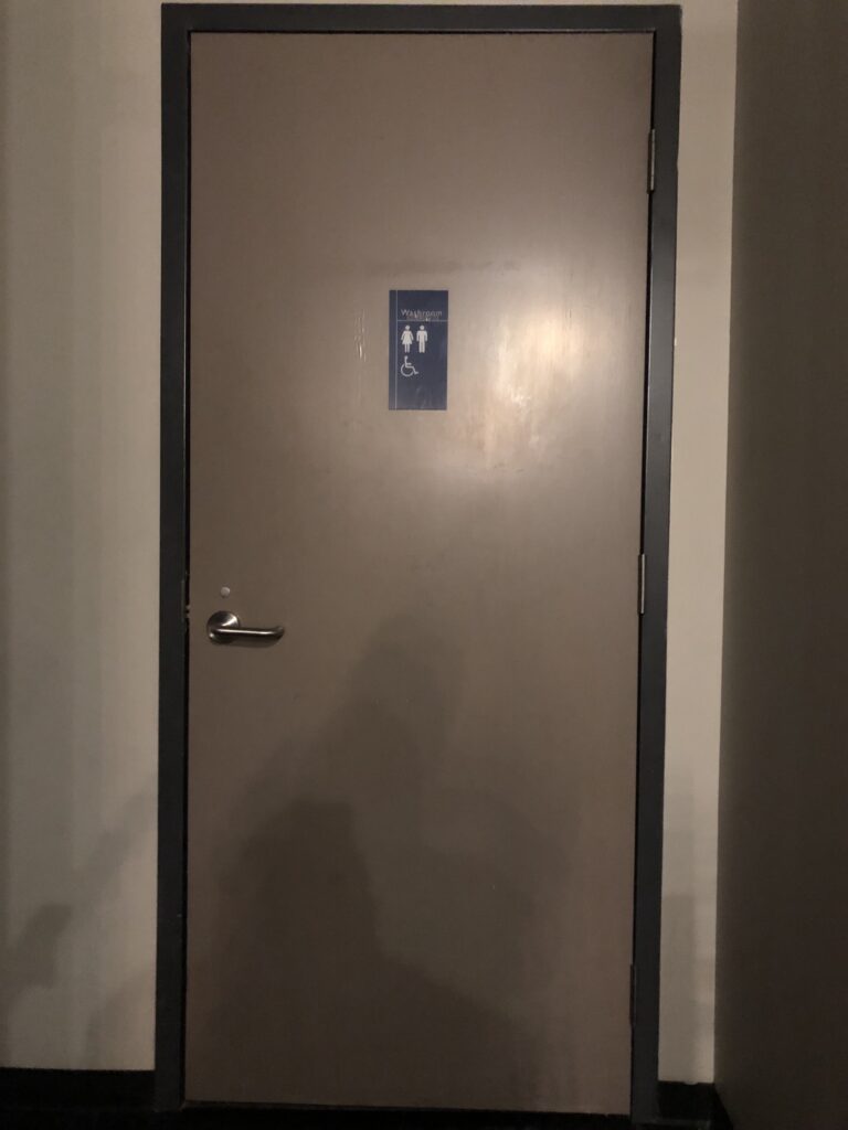 Une porte avec un panneau indiquant des toilettes accessibles.